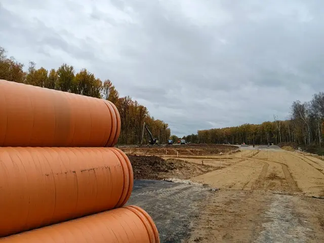 Дорожные работы: оранжевые трубы и экскаватор вдали